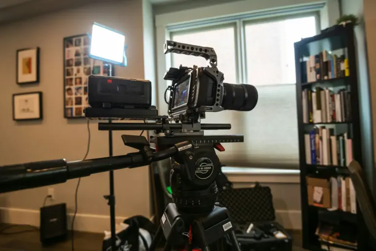Caméra professionnelle installée sur trépied lors d’un tournage en intérieur, avec éclairage et matériel de production.