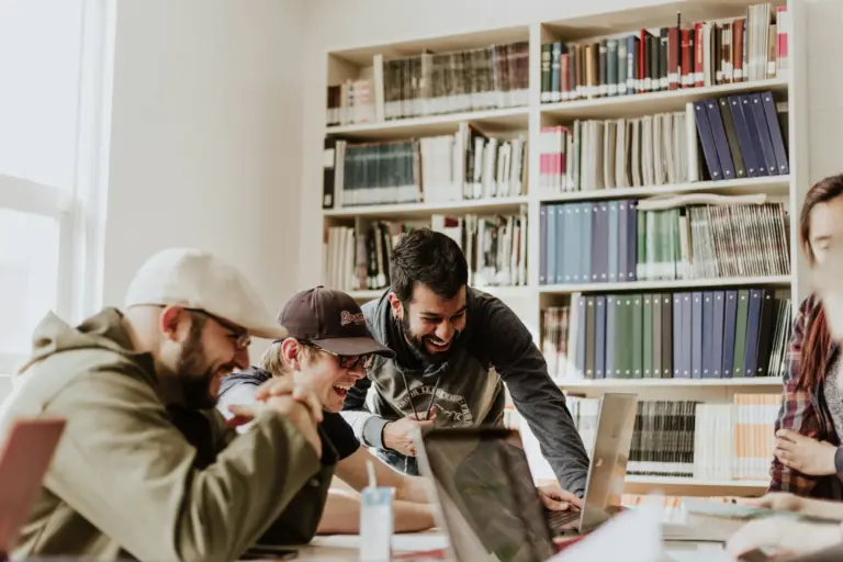 Jeunes professionnels souriants réunis autour d’un ordinateur dans un espace de travail collaboratif.