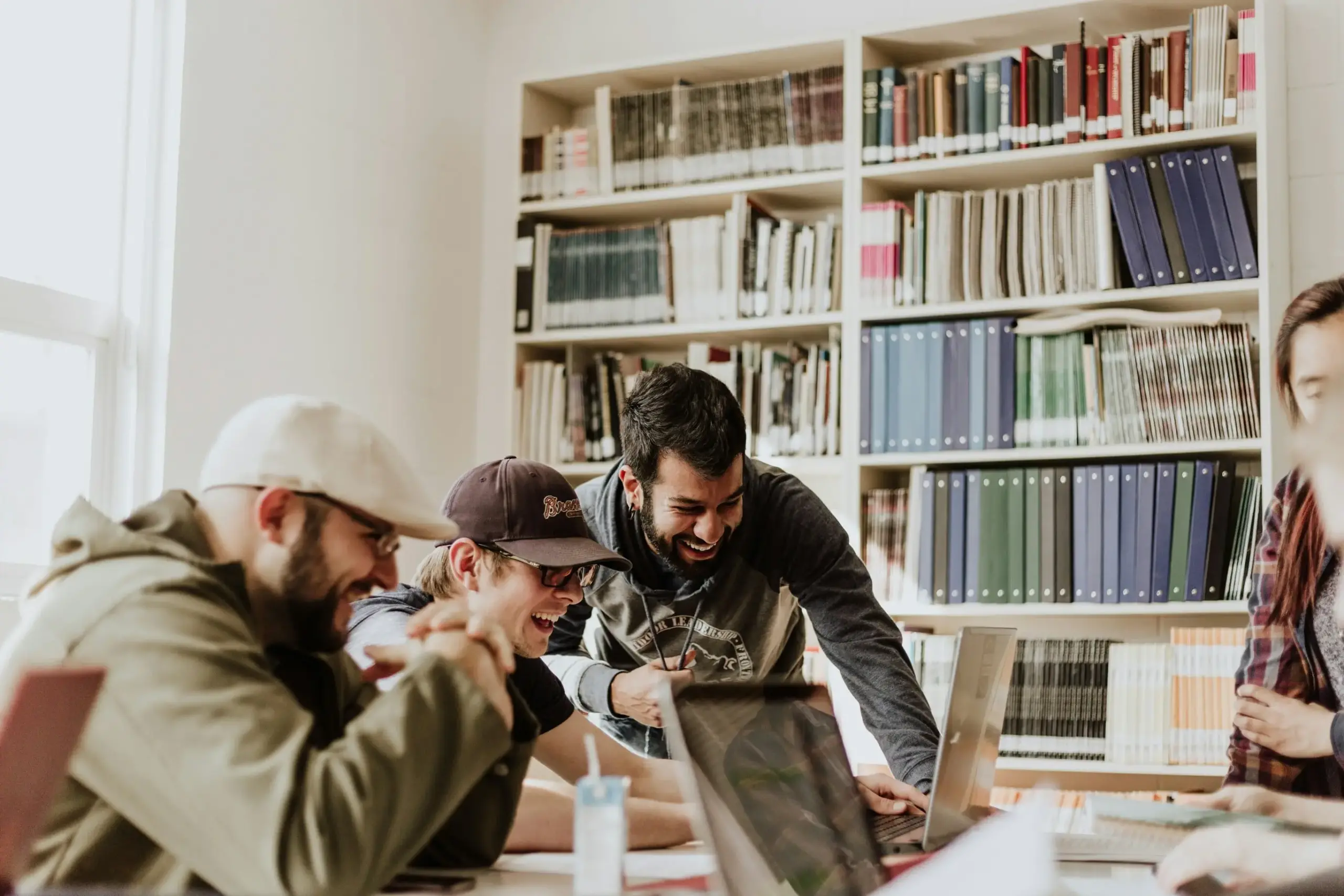 Jeunes professionnels souriants réunis autour d’un ordinateur dans un espace de travail collaboratif.