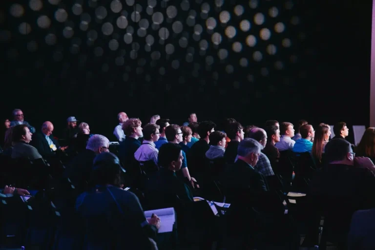 Conférence professionnelle avec participants assistés à une présentation lors d’un événement institutionnel.