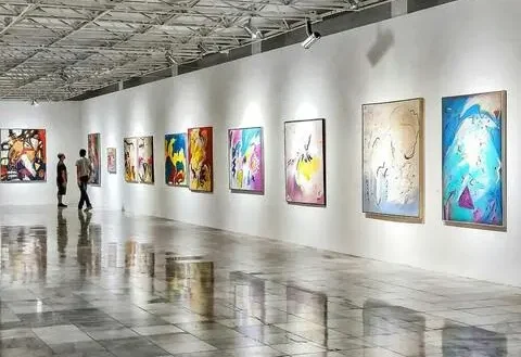 Salle d’exposition d’un centre culturel avec des œuvres contemporaines accrochées aux murs, éclairage muséal et visiteurs en déambulation.